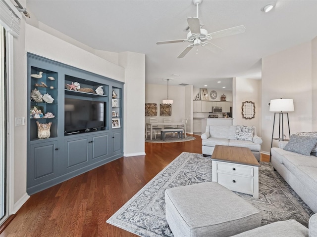 living room with ceiling fan, dark hardwood / wood-style flooring, and built in shelves