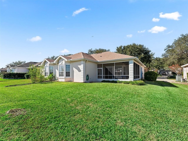 rear view of house featuring a lawn and a sunroom