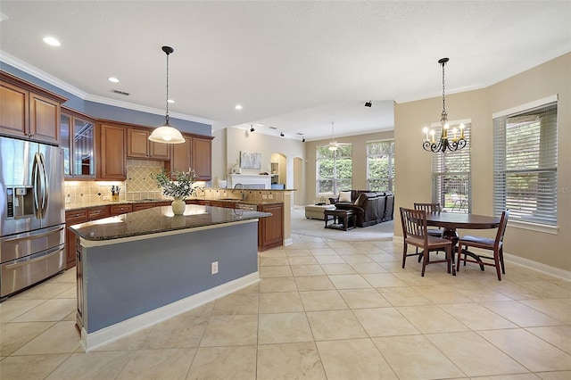 kitchen with sink, hanging light fixtures, stainless steel fridge, dark stone counters, and light tile patterned flooring