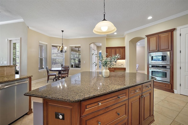 kitchen featuring a kitchen island, stainless steel appliances, hanging light fixtures, and an inviting chandelier