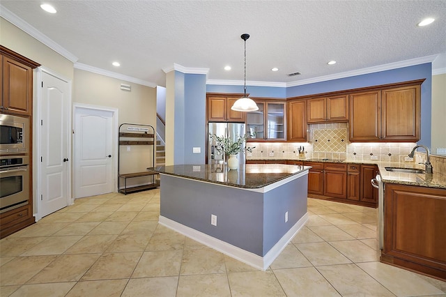 kitchen with sink, a center island, dark stone countertops, light tile patterned flooring, and appliances with stainless steel finishes