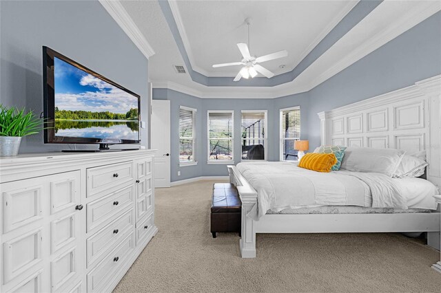 bedroom featuring ornamental molding, a tray ceiling, ceiling fan, and light colored carpet