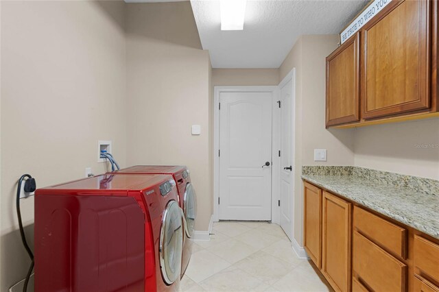 clothes washing area with washing machine and clothes dryer and cabinets