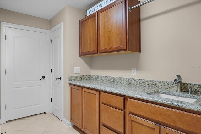 kitchen with light stone counters, light tile patterned floors, and sink