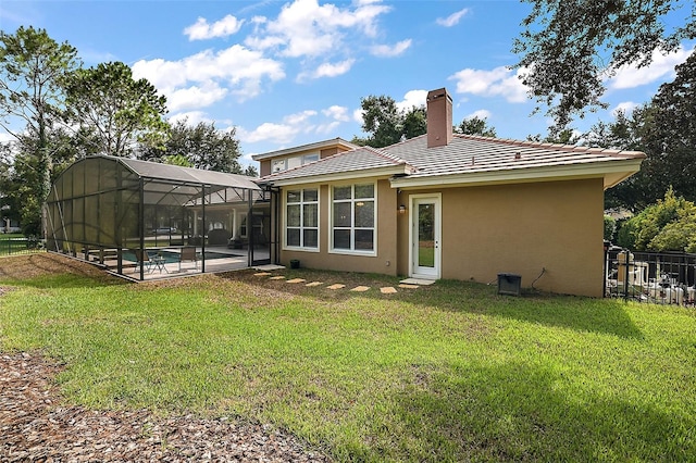 rear view of property with a lanai, a swimming pool, and a yard