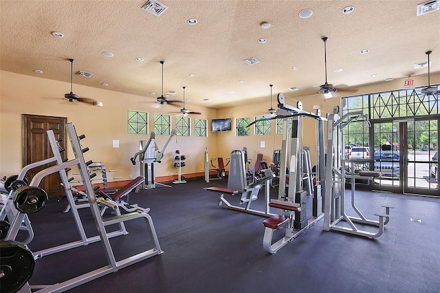 exercise room with ceiling fan and a textured ceiling