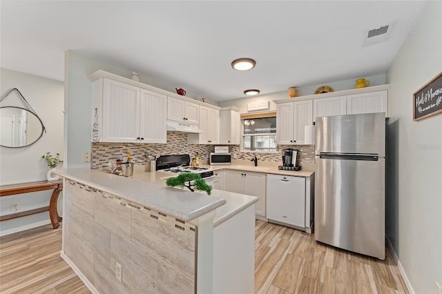 kitchen with white cabinetry, appliances with stainless steel finishes, kitchen peninsula, and decorative backsplash