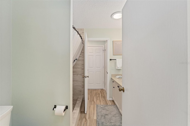 bathroom featuring toilet, a textured ceiling, vanity, a shower with shower curtain, and hardwood / wood-style flooring