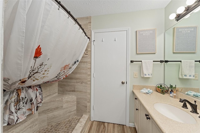 bathroom featuring a shower with curtain, vanity, hardwood / wood-style floors, and a textured ceiling