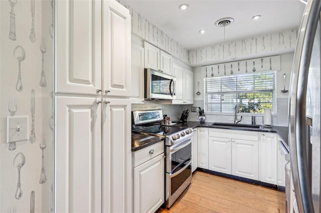 kitchen featuring white cabinets, sink, appliances with stainless steel finishes, and light hardwood / wood-style flooring