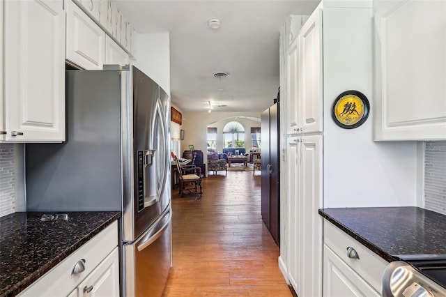 kitchen featuring dark stone counters, white cabinets, light hardwood / wood-style flooring, stainless steel fridge, and range