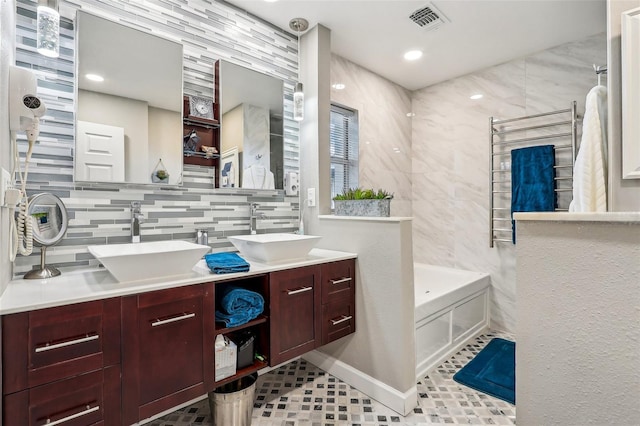 bathroom with backsplash, tile patterned floors, a bathtub, vanity, and tile walls