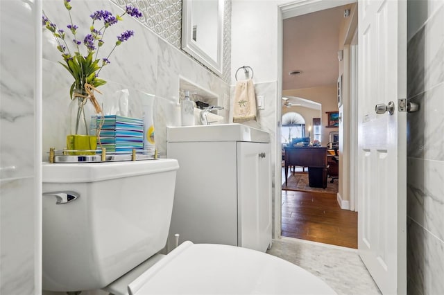 bathroom with sink, hardwood / wood-style floors, tile walls, and toilet