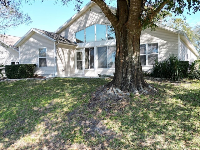 back of house featuring a sunroom and a lawn