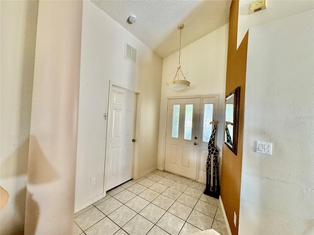 foyer entrance featuring light tile patterned floors, a textured ceiling, and high vaulted ceiling