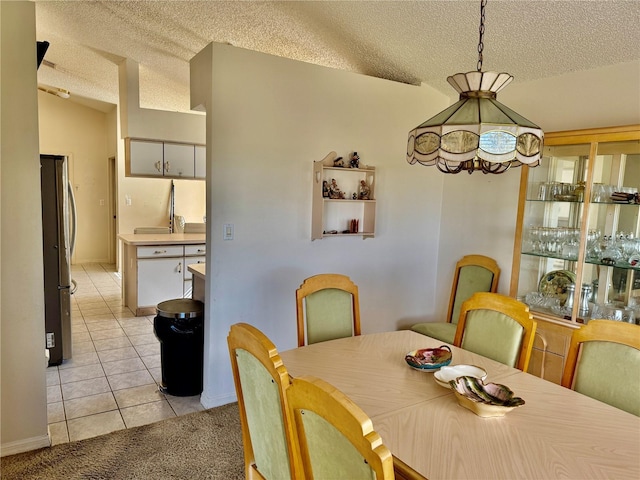 dining space with a textured ceiling, light tile patterned floors, and lofted ceiling