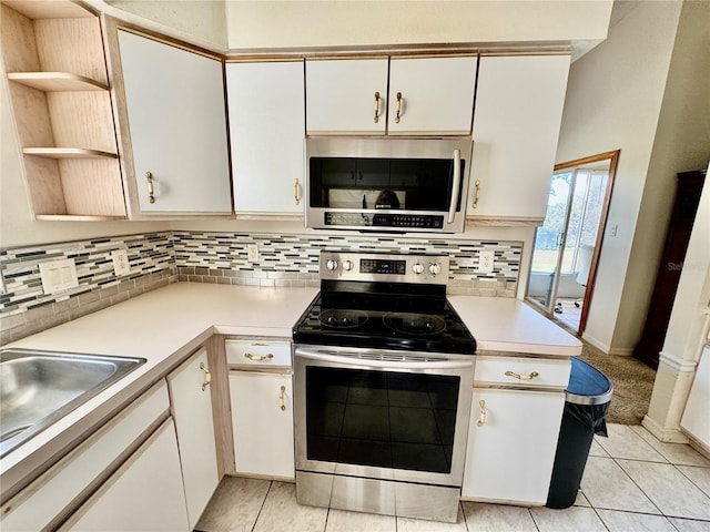 kitchen with tasteful backsplash, white cabinets, stainless steel appliances, and light tile patterned floors