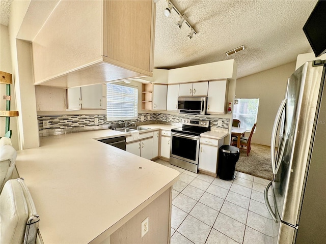 kitchen with rail lighting, sink, tasteful backsplash, kitchen peninsula, and stainless steel appliances