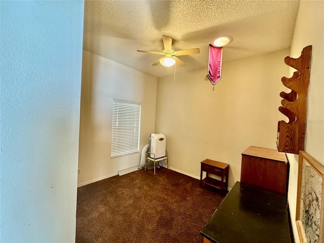 interior space featuring ceiling fan, a textured ceiling, and dark colored carpet