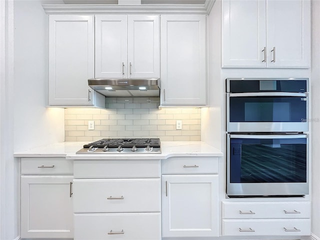 kitchen featuring decorative backsplash, white cabinetry, stainless steel appliances, and light stone counters