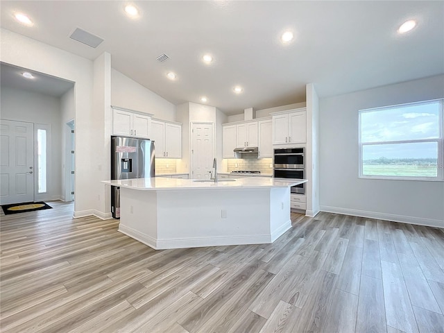 kitchen featuring tasteful backsplash, white cabinetry, a center island with sink, and sink