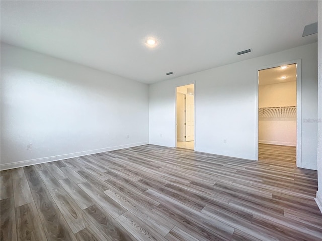 unfurnished bedroom with light hardwood / wood-style flooring, a spacious closet, and a closet