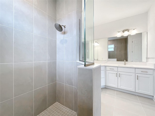 bathroom with a tile shower, vanity, and tile patterned floors