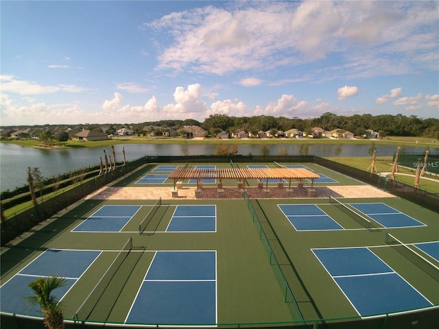 view of tennis court with basketball hoop and a water view