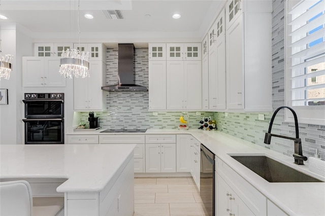 kitchen with hanging light fixtures, white cabinets, and wall chimney exhaust hood