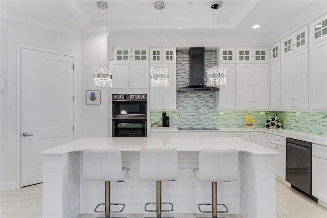 kitchen with black appliances, a kitchen island, a kitchen breakfast bar, and wall chimney exhaust hood