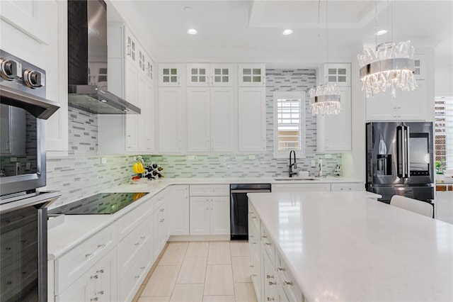 kitchen with sink, an inviting chandelier, stainless steel appliances, white cabinets, and wall chimney exhaust hood