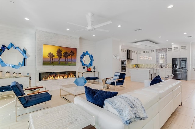 living room featuring ceiling fan, sink, light tile patterned floors, and a fireplace