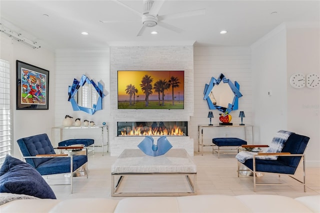 sitting room featuring crown molding, a large fireplace, and ceiling fan