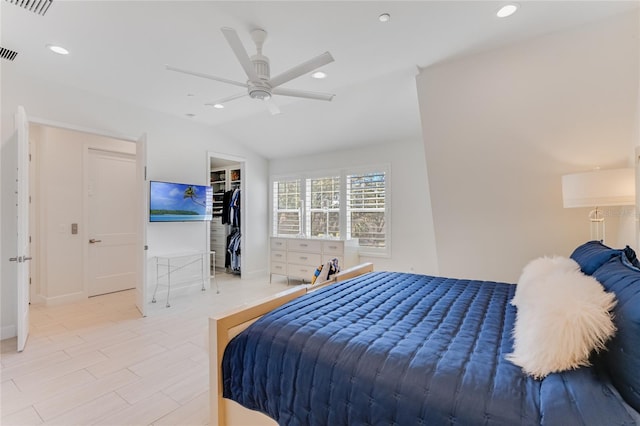 bedroom with a walk in closet, a closet, ceiling fan, and vaulted ceiling