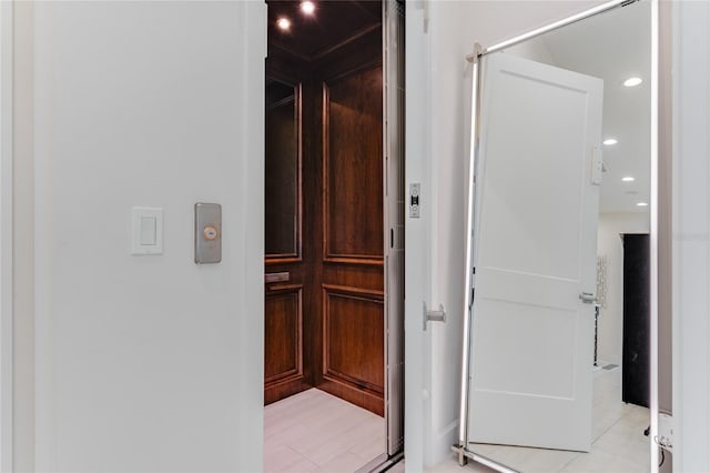 hallway with elevator and light tile patterned floors