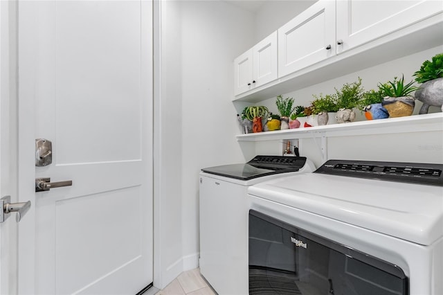 washroom featuring light tile patterned flooring, cabinets, and washer and dryer