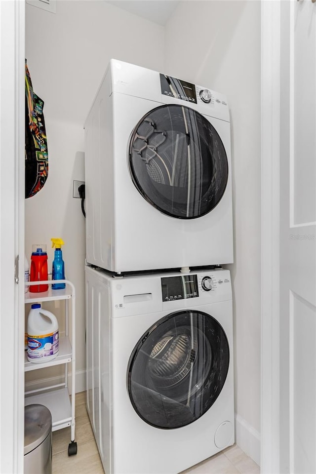 clothes washing area with stacked washing maching and dryer