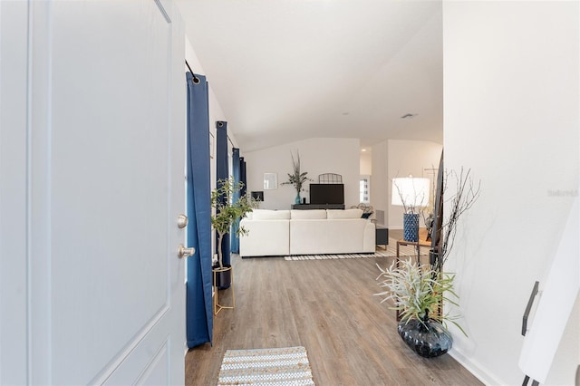 hall featuring hardwood / wood-style flooring and vaulted ceiling