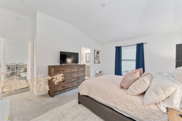 bedroom featuring connected bathroom, vaulted ceiling, and light colored carpet