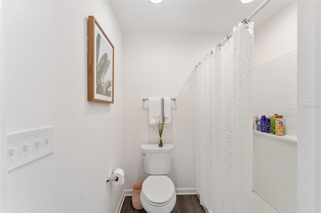 bathroom with a shower with shower curtain, hardwood / wood-style floors, and toilet