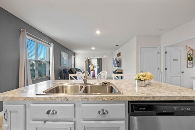 kitchen featuring stainless steel dishwasher, sink, white cabinets, and an island with sink