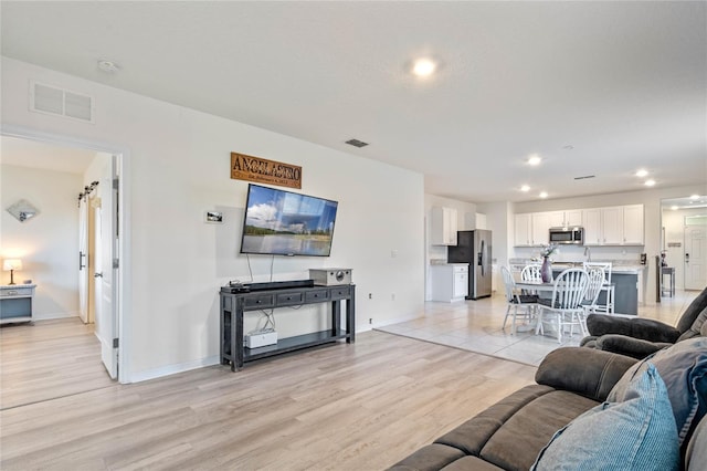 living room featuring light wood-type flooring and a barn door