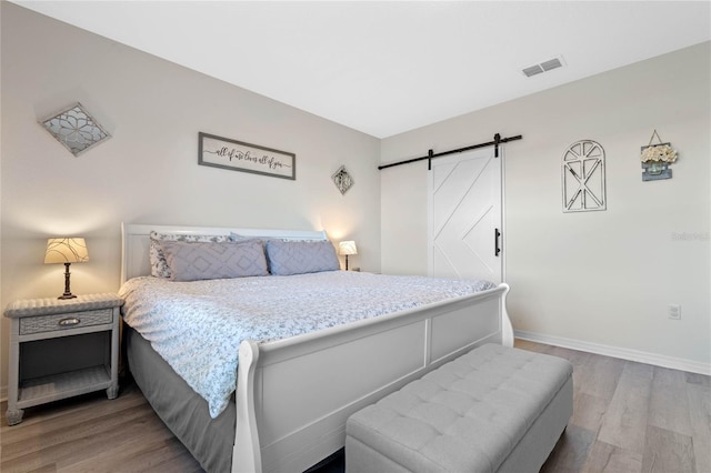 bedroom featuring a barn door and hardwood / wood-style flooring