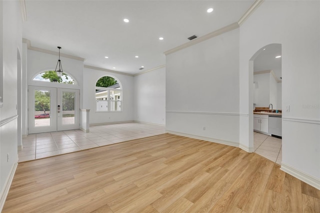 11941 Graces Way, Clermont, FL 34711 - spare room featuring crown molding, light wood-style flooring, arched walkways, recessed lighting, and french doors