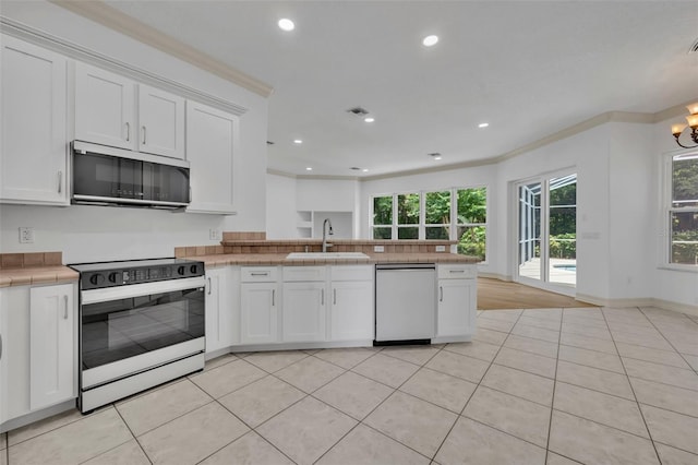 11941 Graces Way, Clermont, FL 34711 - kitchen featuring white appliances, a peninsula, white cabinets, light tile patterned flooring, and healthy amount of natural light