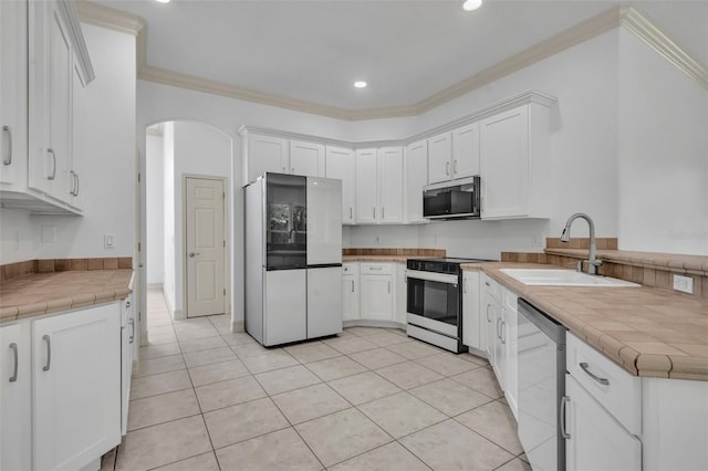 11941 Graces Way, Clermont, FL 34711 - kitchen with stainless steel appliances, crown molding, white cabinets, arched walkways, and recessed lighting