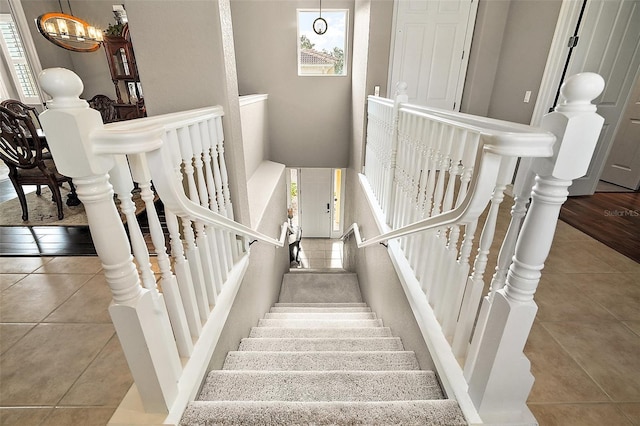 stairway featuring tile patterned flooring and a notable chandelier