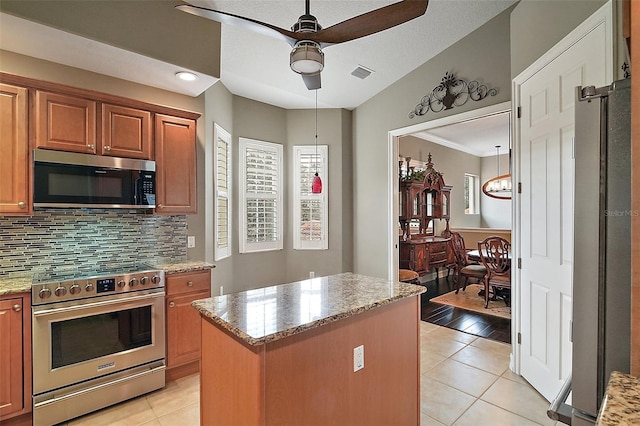 kitchen featuring a kitchen island, stainless steel appliances, light tile patterned floors, and tasteful backsplash