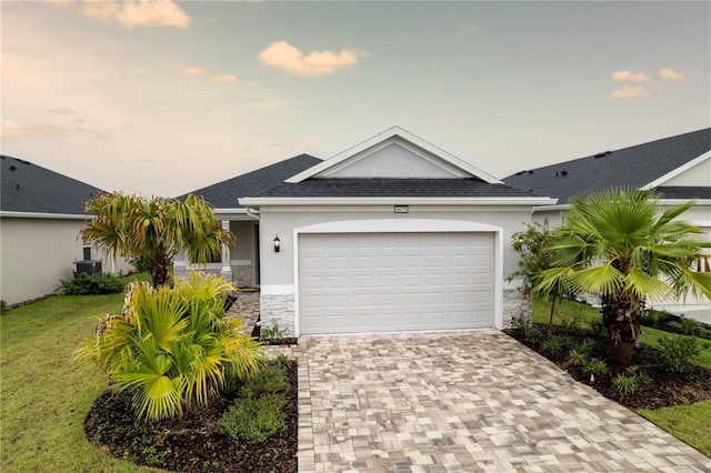 single story home with a lawn, a garage, and central AC