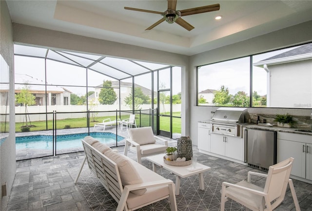 sunroom featuring ceiling fan, a raised ceiling, sink, and a pool